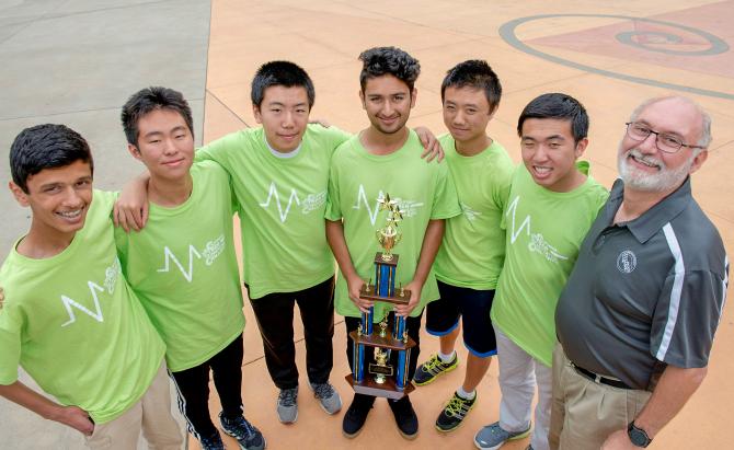 students wearing light green t-shirts holding a trophy