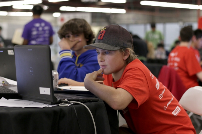 student in orange shirt using laptop
