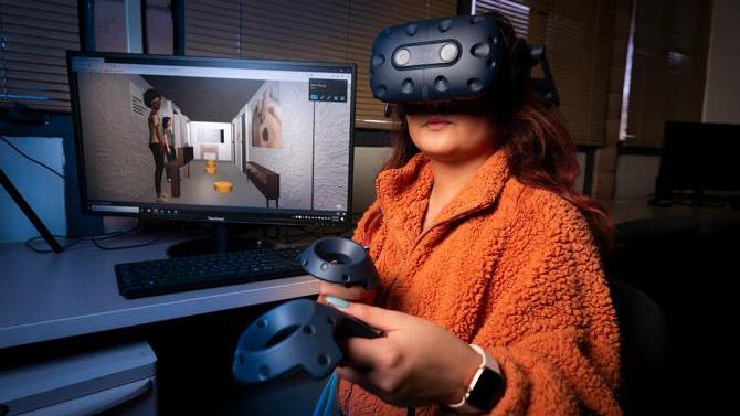 Cal Poly computer science major Zahnae Aquino uses an HTC VIVE headset and controllers to navigate a virtual reality environment that she created with fellow student Josie Grundler.