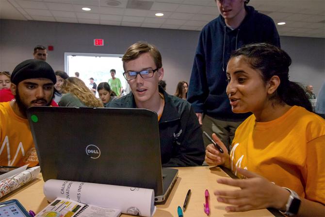 three students looking at a computer screen with surprised expressions
